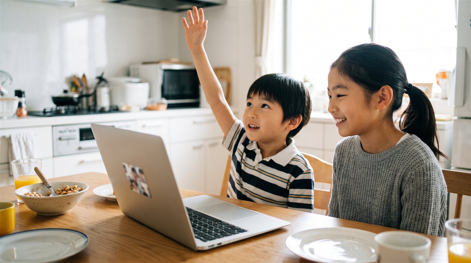 Siblings joining an online group Japanese lesson together at the kitchen table, the younger brother raising his hand
