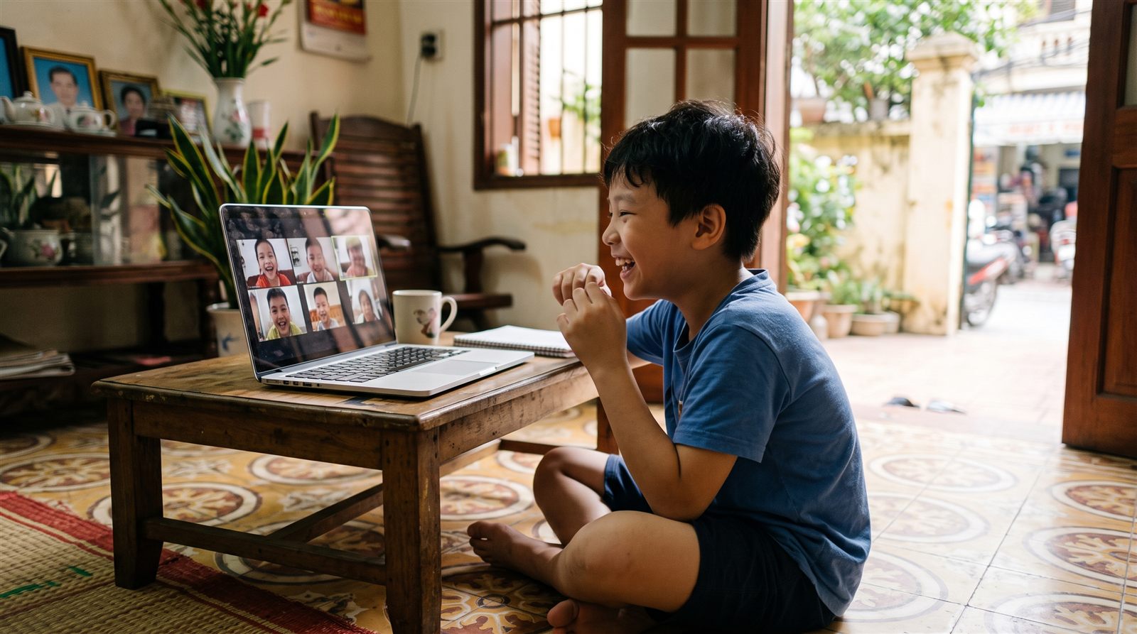 A child in Ho Chi Minh City laughing during an online group video call with friends in Japan before dinner
